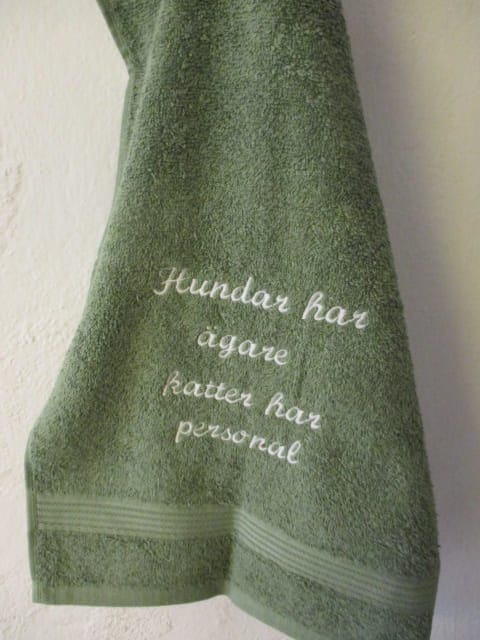 Frottehandduk med maskinbroderat motiv, "Hundar har ägare, katter har personal". 30 x 50 cm. Grön.