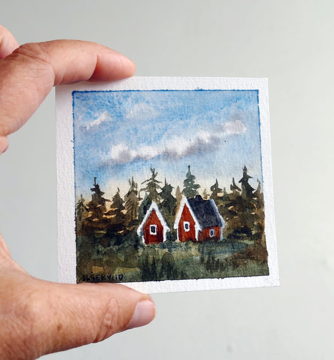 Liten original akvarellmålning. Röda stugor i skogen.