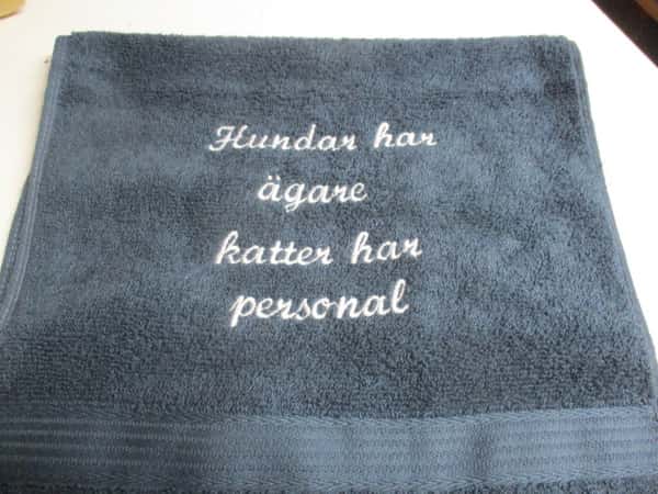 Frottehandduk med maskinbroderat motiv, "Hundar har ägare, katter har personal". 30 x 50 cm. Mörkblå.