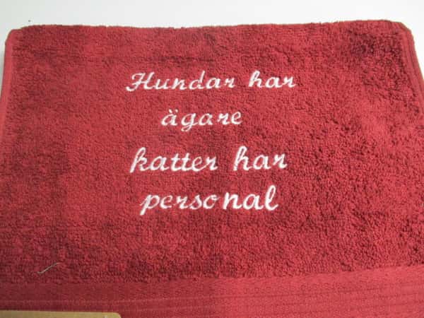 Frottehandduk med maskinbroderat motiv, "Hundar har ägare, katter har personal". 30 x 50 cm. Vinröd