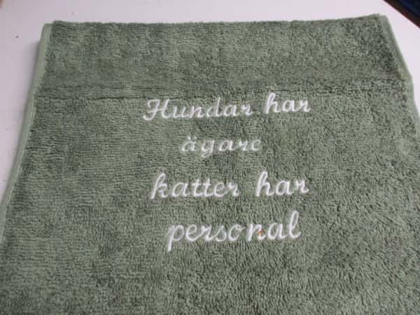 Frottehandduk med maskinbroderat motiv, "Hundar har ägare, katter har personal". 30 x 50 cm. Grön.